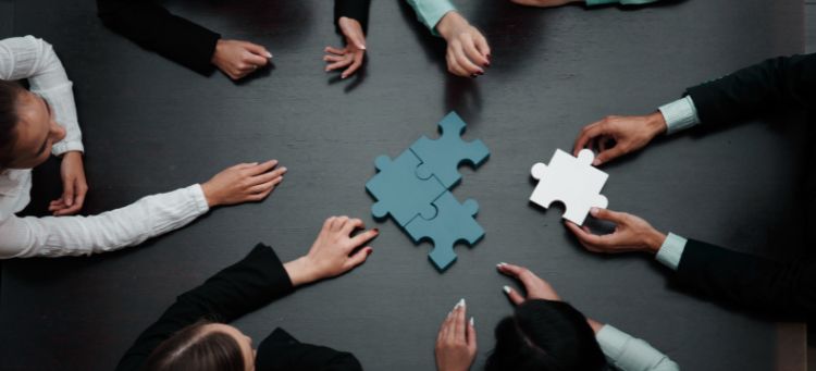 Equipe empresarial resolvendo quebra-cabeça em referência ao diferencial competitivo de soluções de auditoria e consultoria